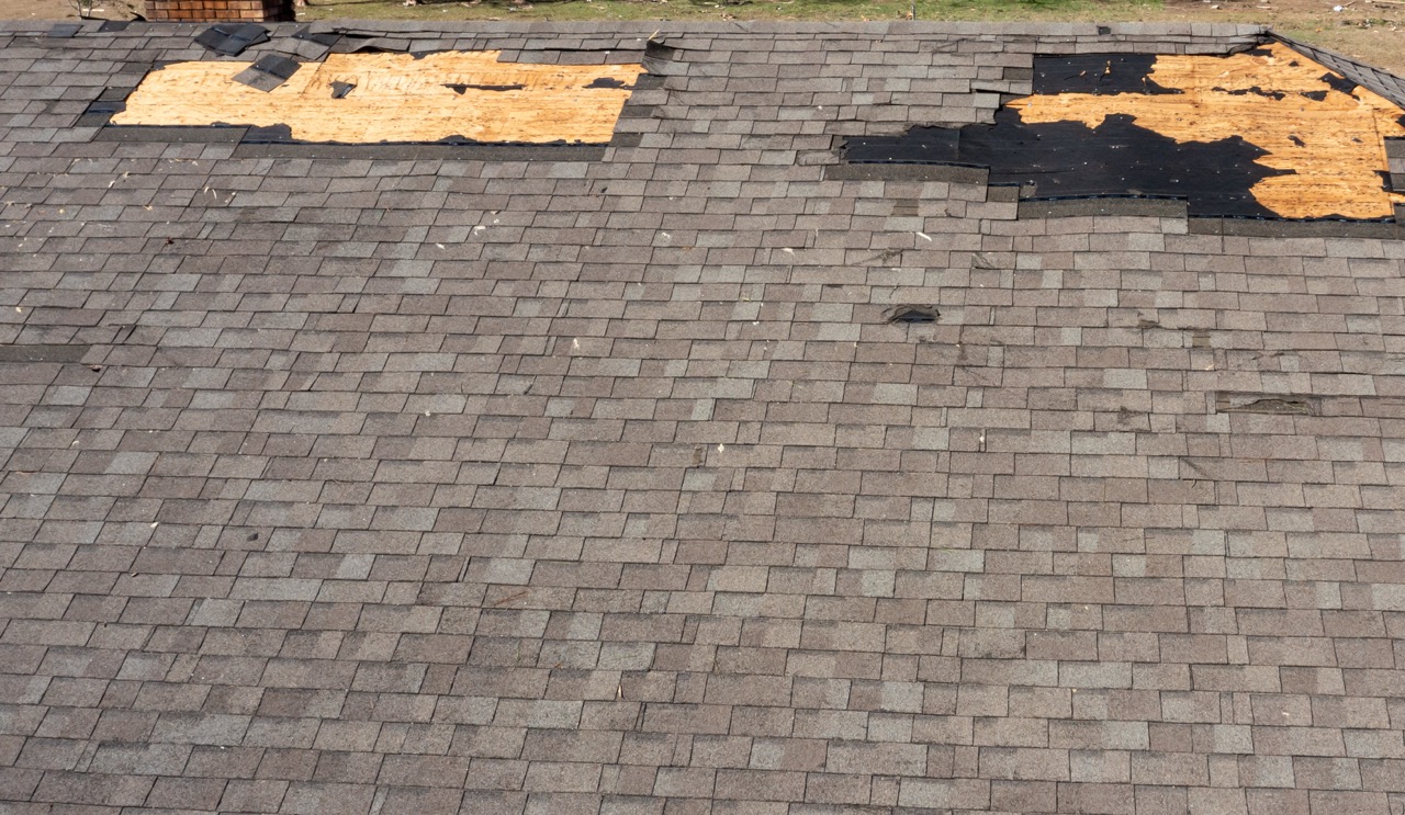 Roof with missing shingles, damaged by tornado during severe weather